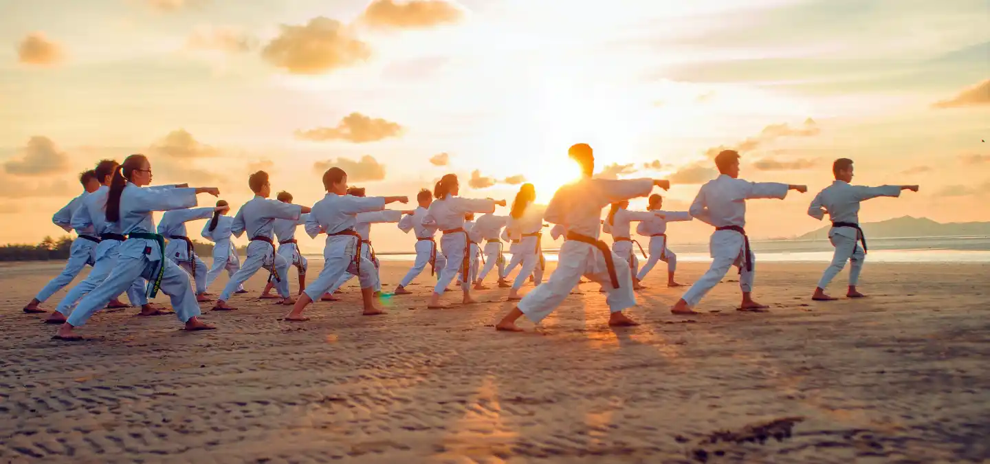 benefici fisici e mentali del karate - Allievi che praticano sulla spiaggia al tramonto